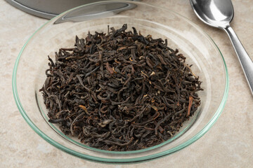 Wall Mural - Glass bowl with dried aromatic Indian Assam tea leaves close up  