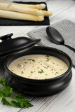 Fototapeta Kuchnia - Delicious white asparagus cream soup on wooden background