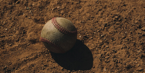 Sticker - Old used baseball ball in game field dirt with copy space on background for summer sport.