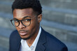 © Mediaphotos - Close-up of young Black businessman in eyeglasses raising eyebrow in puzzlement, he looking at camera outdoors