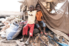Two Young Desperate African Children Sitting On Tires And Waste On A Huge Garbage Dump In A Village Near Bamako, In Mali (Africa).