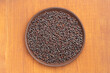 Spice Mustard seeds (Brassica juncea) in brown clay plate on brown wooden background. Close up. Healthy eating concept