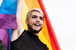 © Vane Nunes - Gay transgender man with makeup holding rainbow flag outdoor - LGBTQ drag queen concept
