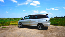 Silver Modern Minivan. Japanese Car. Located In Nature. Sunny Day. Blue Sky. Travel By Car. Family Transport. Side View.
