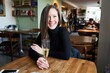 © nyul - Portrait of a young white woman sitting at table smiling feeling happy and drinking champagne in cafe.