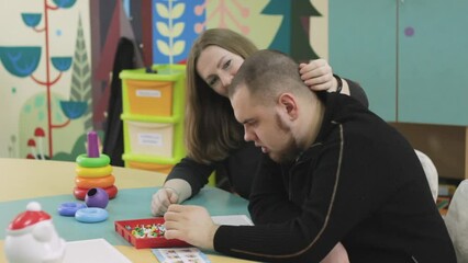 Wall Mural - A female psychologist works with an adult boy with autism in the office. The concept of autism