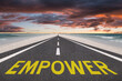 © jaykoppelman - The word Empower on a highway at the beach leading into the sunset.