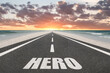 © Jay Koppelman - The word Hero on a road at sunset leading to the horizon for motivational concept.