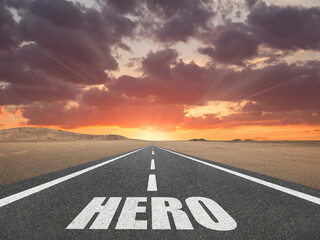 The word Hero on a road at sunset leading to the horizon for motivational concept.
