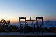 Wooden blue table and chair on the shore of the blue sea. Seaside cafe at evening sunset.