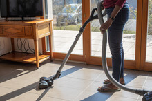 Woman Hoovering Floor At Home Using Vacuum Cleaner