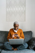 © Ezequiel Giménez/Stocksy - Lady with laptop using cellphone while sitting on couch