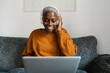 © Ezequiel Giménez/Stocksy - Woman in headphones chilling with laptop at home