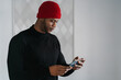 © Ezequiel Giménez/Stocksy - Serious black male messaging on smartphone in apartment