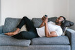 © Ezequiel Giménez/Stocksy - Barefoot black man chilling on couch