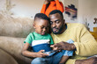 © Pedro Merino/Stocksy - Father and son playing with a game console