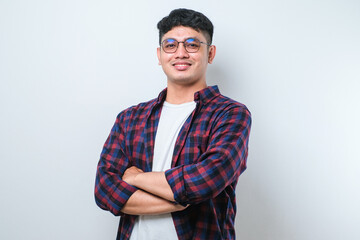 portrait of young handsome asian man wearing casual shirt and glasses standing with arms crossed and