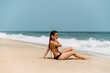 © David Prado/Stocksy - Slim woman in bikini standing on sandy beach