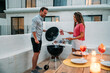 © David Prado/Stocksy - Happy couple preparing food on terrace