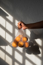 Oranges In A White Recyclable Mesh Bag Held By A Male Right Hand
