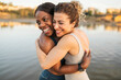 © Lupe Rodríguez/Stocksy - Middle-aged multiracial female friends embrace on a river jetty