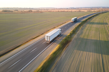Wall Mural - Aerial view of cargo trucks driving on highway hauling goods. Delivery transportation and logistics concept