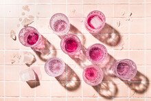 Glass Tumblers On A Pink Tile Counter With Pink Liquid And Ice.