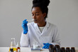 © ALTO IMAGES/Stocksy - Black pharmacist sniffing natural skincare product