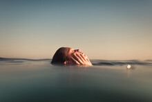 Woman Floating On The Ocean With Hands Touching Her Face