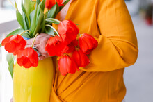 Crop Woman Holding Yellow Vase With Red Tulips 