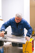 © David Prado/Stocksy - Mature handyman cutting countertop with jigsaw