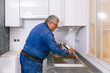 © David Prado/Stocksy - worker installing sink in kitchen