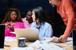 © Guille Faingold/Stocksy - Asian woman talking with coworkers
