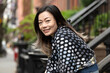 © Lauren Lee/Stocksy - Woman smiling at camera in neighborhood