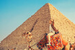 Tourist man with hat riding on camel background pyramid of Egyptian Giza, sunset Cairo, Egypt