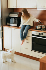 girl 9 years old with long hair model schoolgirl at home lifestyle in a beige kitchen having fun preparing food on an induction stove cooker