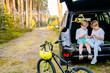 © Iryna - Family picnic outdoor, road trip in autumn season. Two boys sitting at trunk car forest adventure concept.