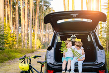 Family Picnic Outdoor, Road Trip In Autumn Season. Two Boys Sitting At Trunk Car Forest Adventure Concept.