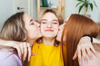 two girls laugh and kiss a friend on the cheek