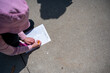 Young girl completing a zoo scavenger hunt form outdoors in the spring.