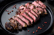Sliced grilled rib eye beef steak beef marbled rare, on plate, on old dark rustic background
