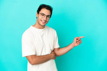 Wall Mural - Caucasian handsome man over isolated blue background pointing finger to the side