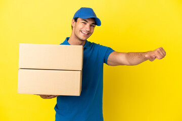 Wall Mural - Delivery man over isolated yellow wall giving a thumbs up gesture