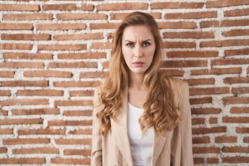 Canvas Print - Beautiful blonde woman standing over bricks wall skeptic and nervous, frowning upset because of problem. negative person.