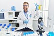 © Krakenimages.com - Middle age man working at scientist laboratory smiling with happy face winking at the camera doing victory sign. number two.