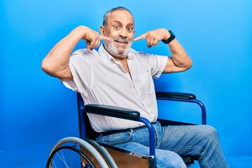 Canvas Print - Handsome senior man with beard sitting on wheelchair smiling cheerful showing and pointing with fingers teeth and mouth. dental health concept.