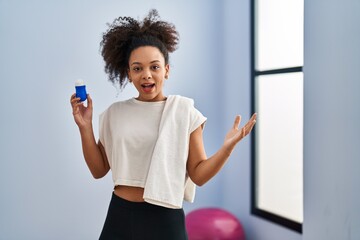 Wall Mural - Young african american woman wearing sportswear and towel holding deodorant celebrating victory with happy smile and winner expression with raised hands