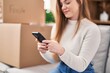 © Krakenimages.com - Young blonde woman smiling confident using smartphone at new home
