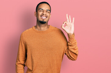 Wall Mural - Young african american man wearing casual clothes smiling positive doing ok sign with hand and fingers. successful expression.