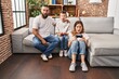 © Krakenimages.com - Family of three playing video game sitting on the sofa scared and amazed with open mouth for surprise, disbelief face